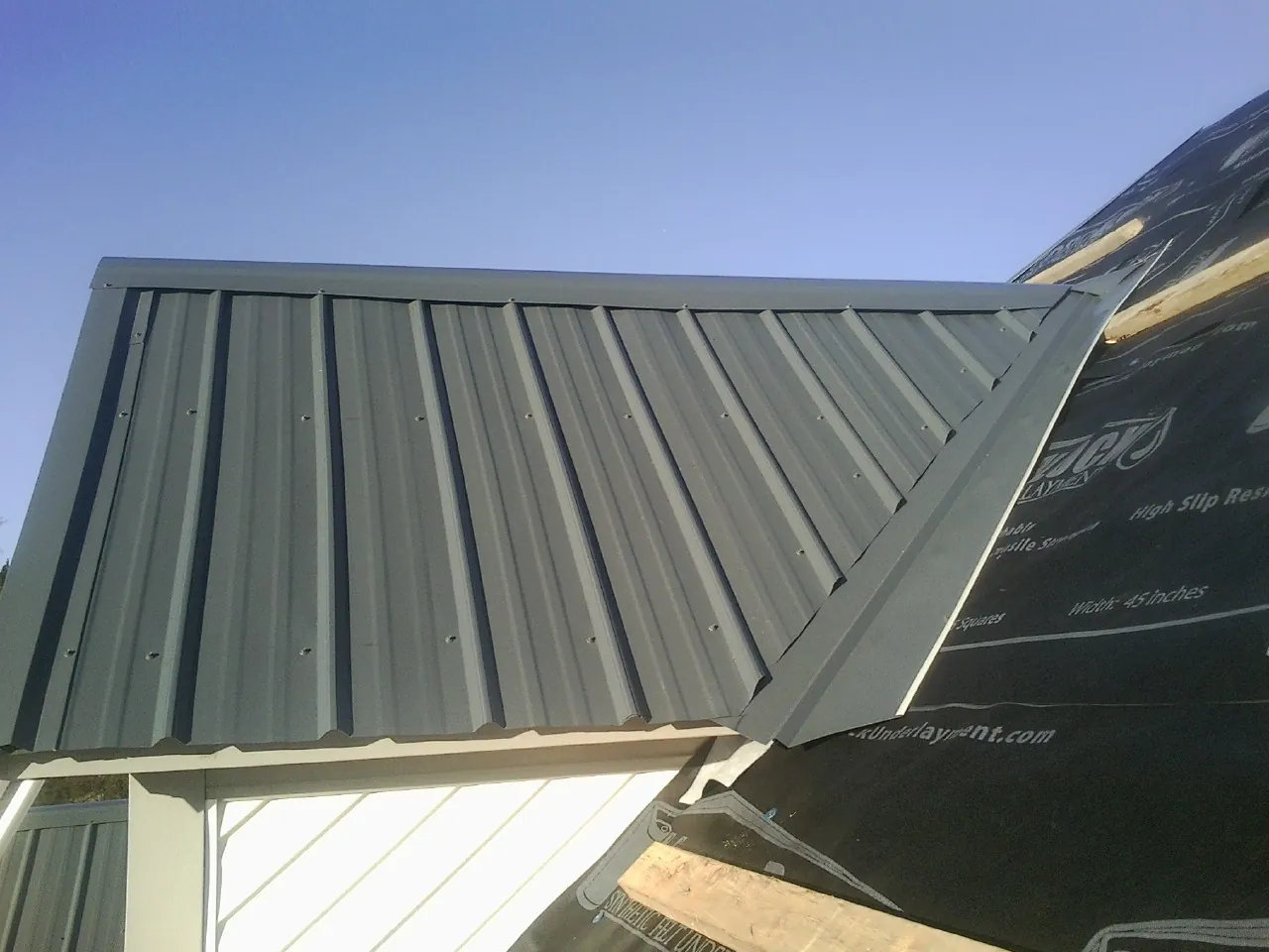 Gray metal roof panels going on over a garage gable in Delta