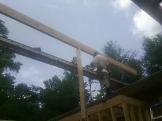 Carpenter setting a ridge beam over a new addition frame — Ice Dam Removal by Roofing Brothers in Delta