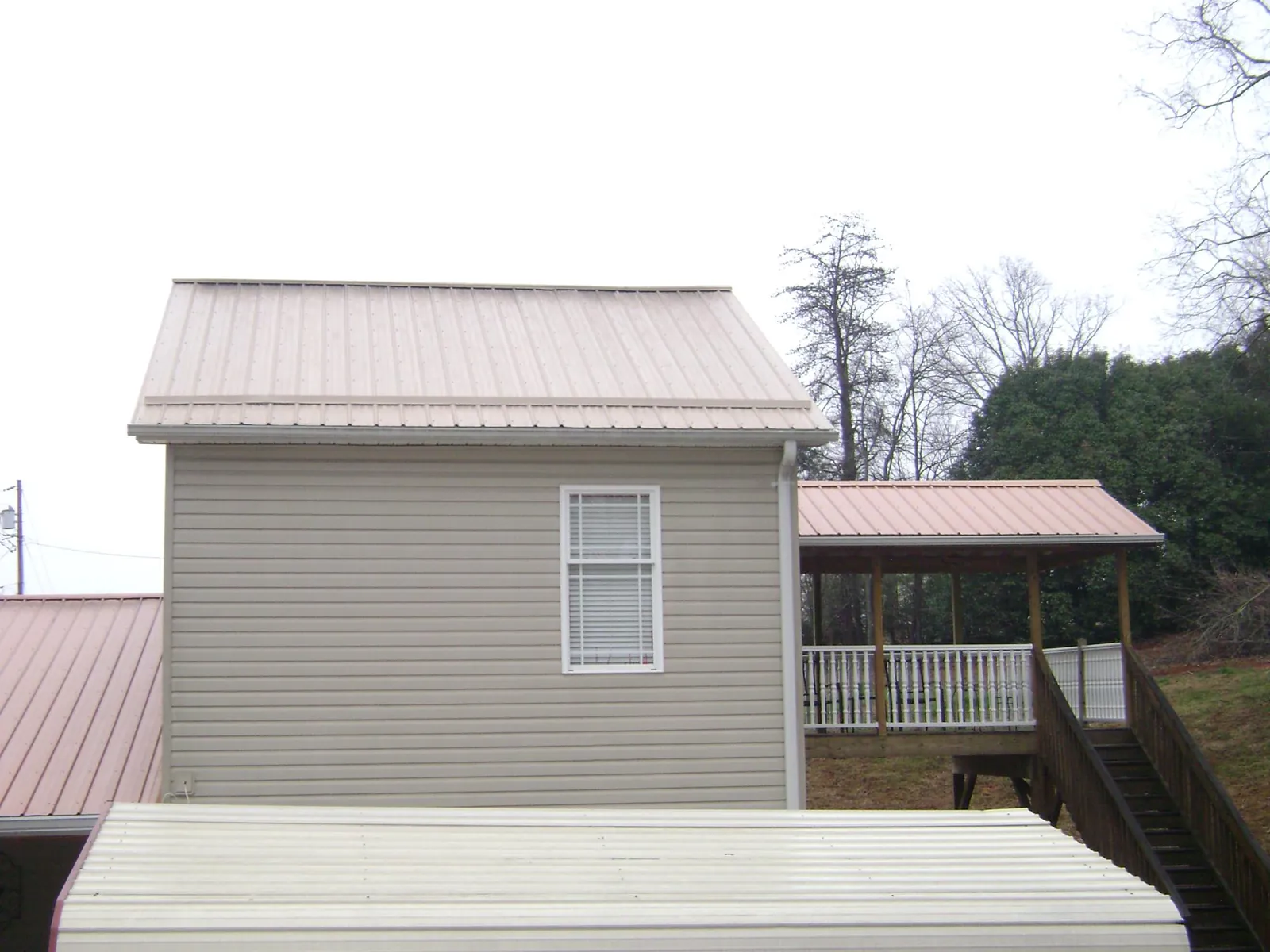 Tan metal roofs on a two story addition and attached porch, from a Roof Replacement job in Delta